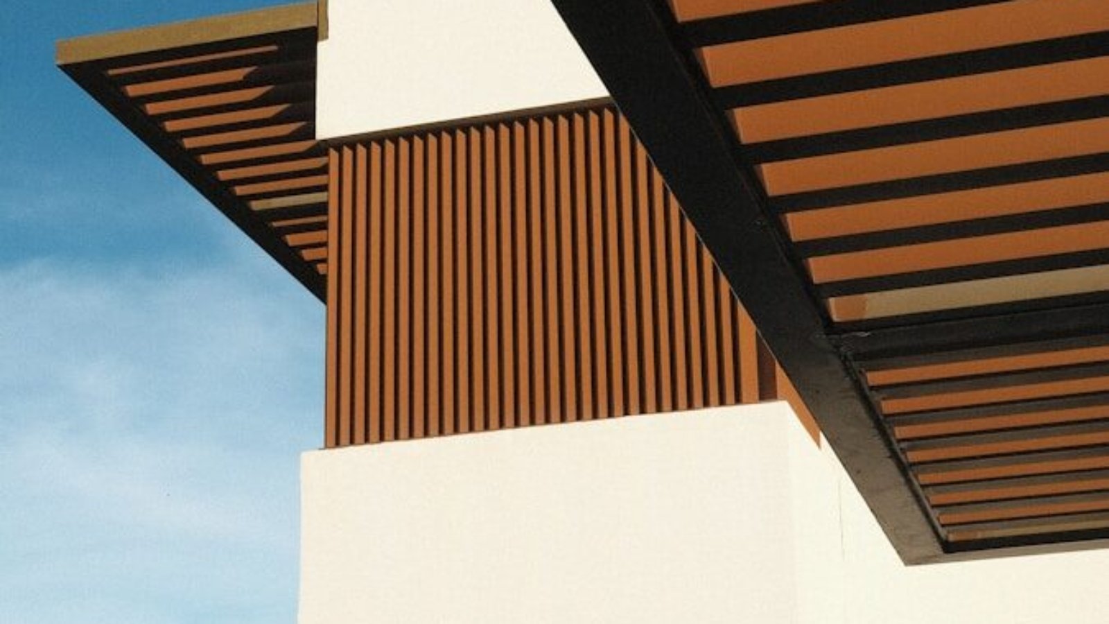 a white building with a wooden roof and a sky background