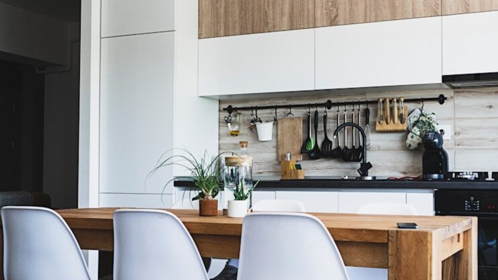 brown wooden dining table with white chairs near kitchen